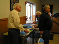 Three Retirees Collecting Frozen Turkeys from Table